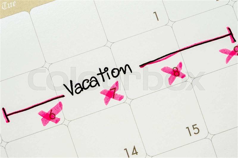 The word vacation is written on a calendar page, stock photo
