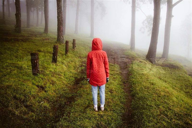 Woman wear red coat turn back looking on path way with fog and misty in rainingday, stock photo