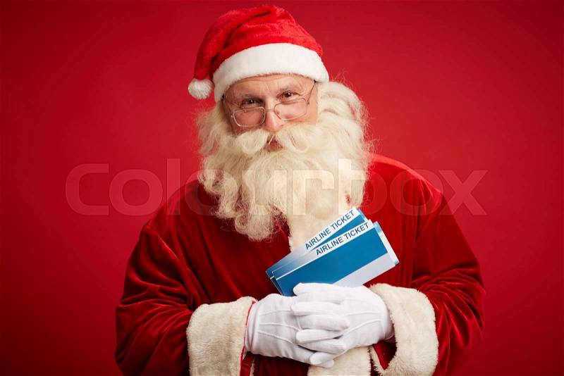 Happy Santa with air tickets looking at camera, stock photo