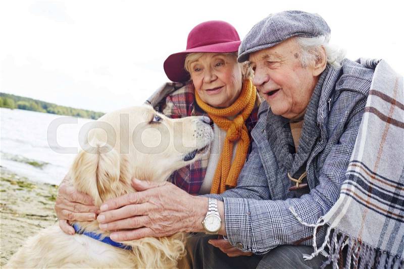 Seniors looking at retriever with pride and love, stock photo