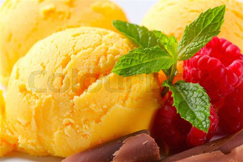 Scoops of yellow ice cream with raspberries and chocolate curls, stock photo