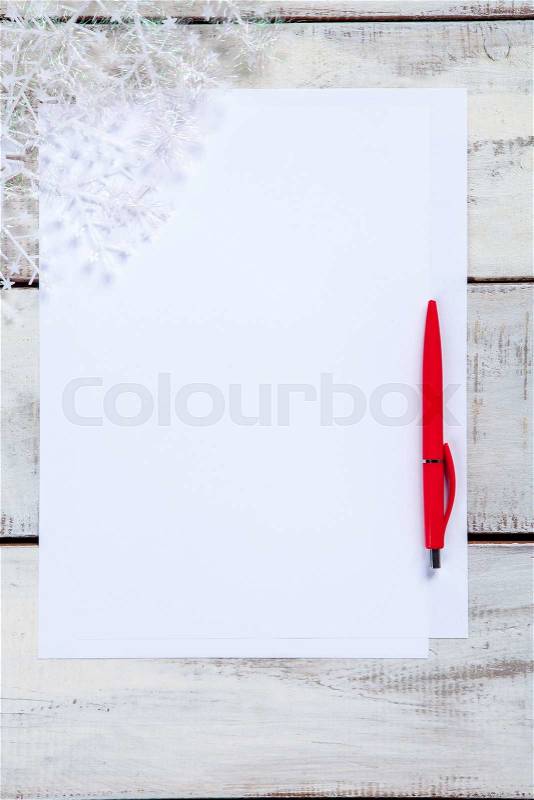 The blank sheet of paper on the wooden table with a pen. Christmas mockup concept, stock photo