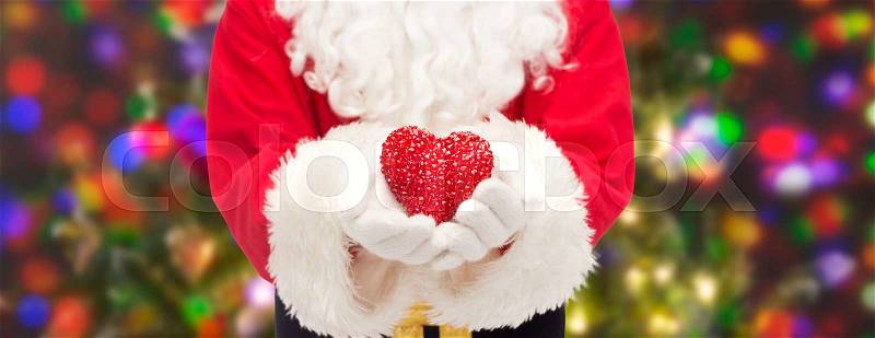 Christmas, holidays, love, charity and people concept - close up of santa claus with heart shape decoration over lights background, stock photo
