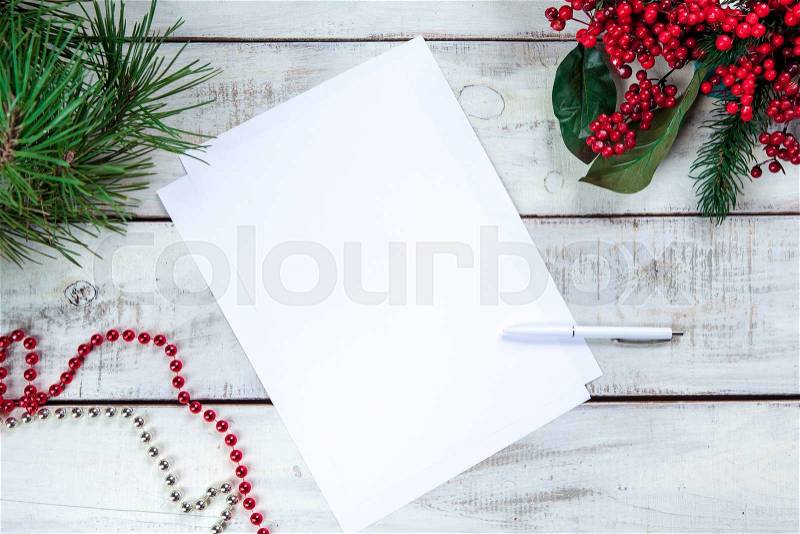 The blank sheet of paper on the wooden table with a pen and Christmas decorations. Christmas mockup concept, stock photo