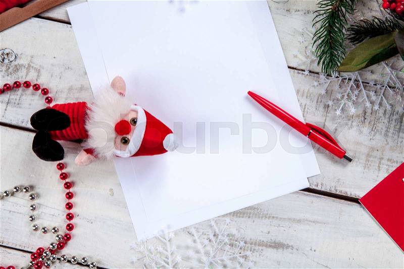 The blank sheet of paper on the wooden table with a pen and Christmas decorations. Christmas mockup concept, stock photo