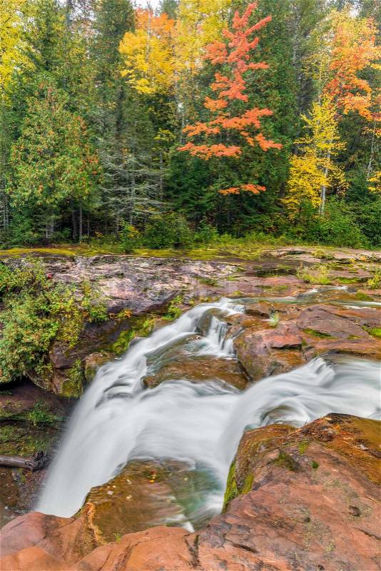 Colorful fall foliage lines the banks of the Baltimore River at O Kun de Kun Falls, a beautiful waterfall in Michigan\'s Upper Peninsula, stock photo