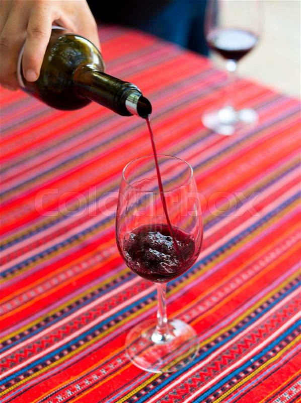 Red wine is pouring into wine glass, stock photo