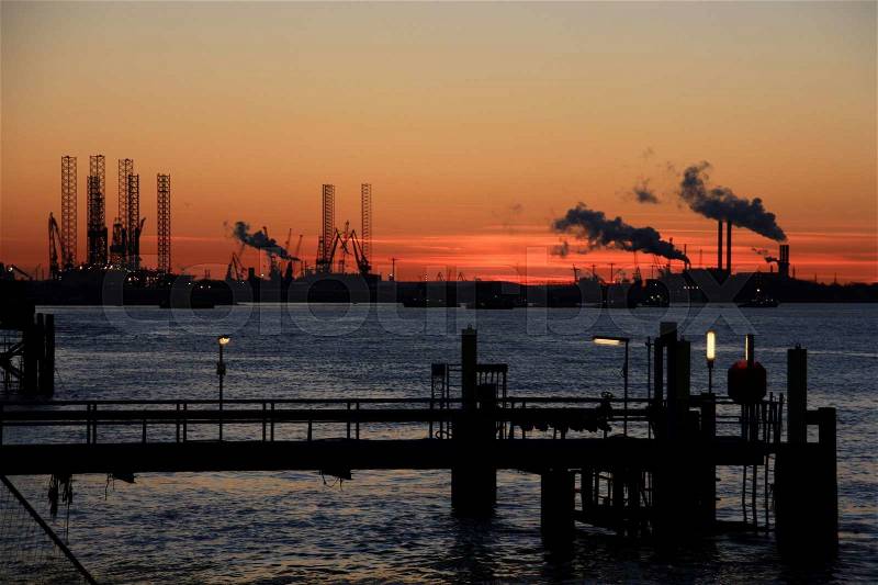 Channel, wharf and industry with smoking chimneys in Rotterdam at sunset in fall, stock photo