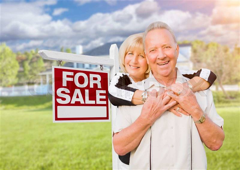 Happy Senior Couple Front of For Sale Real Estate Sign and House, stock photo