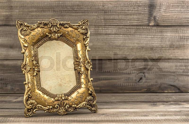 Golden vintage picture frame on wooden background. Baroque style object, stock photo