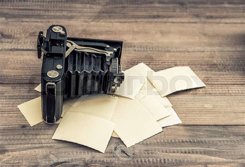 Antique camera and old photos on wooden background. Nostalgic still life. Retro style toned picture, stock photo