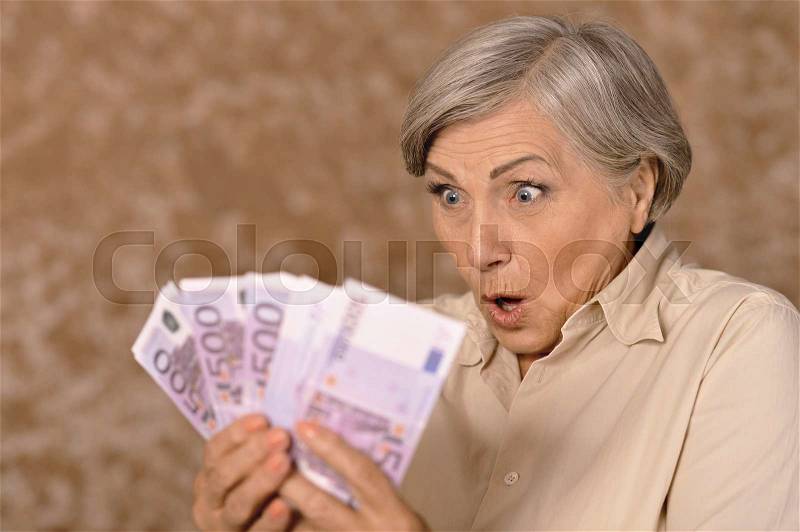 Portrait of an aged woman holding money, stock photo
