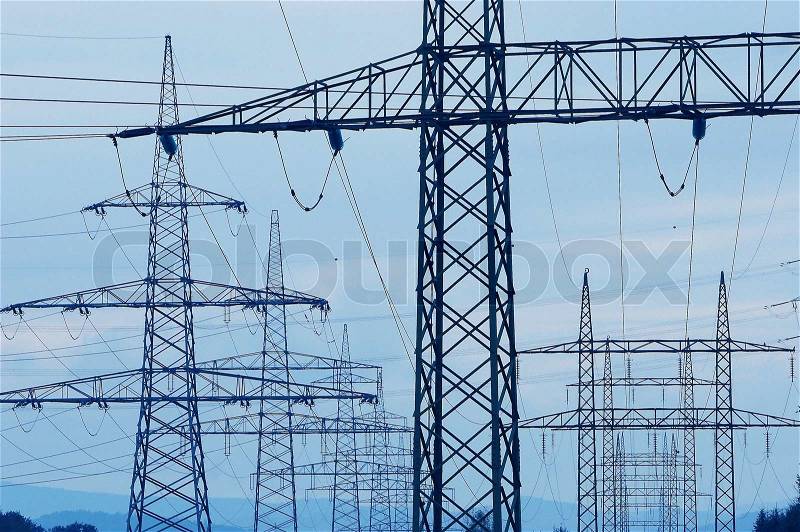 A receding line of steel pylons supporting power transmission lines, stock photo