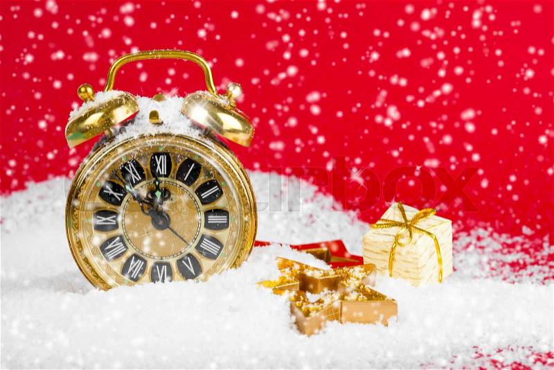 Vintage christmas decoration golden star and antique golden clock in snow on red background, stock photo
