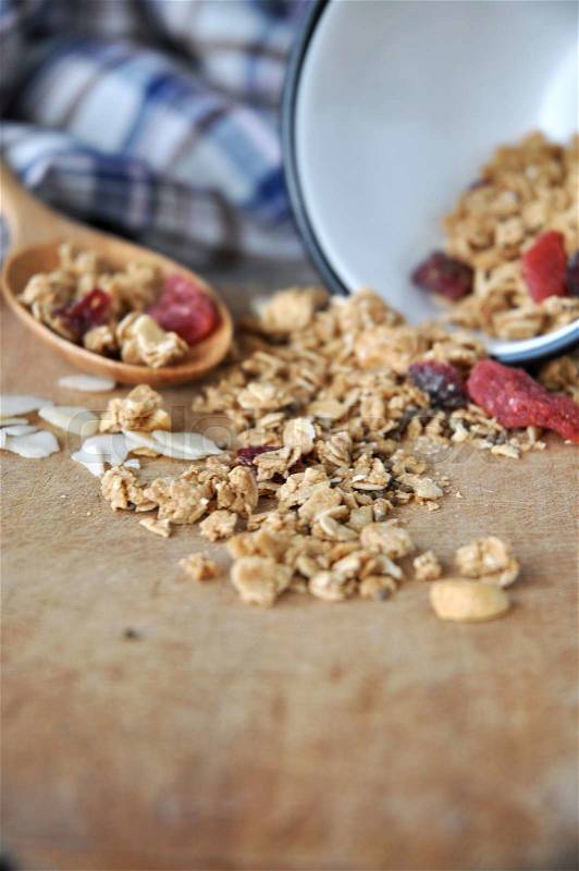Granola bowl spilling on wooden cutting board, stock photo