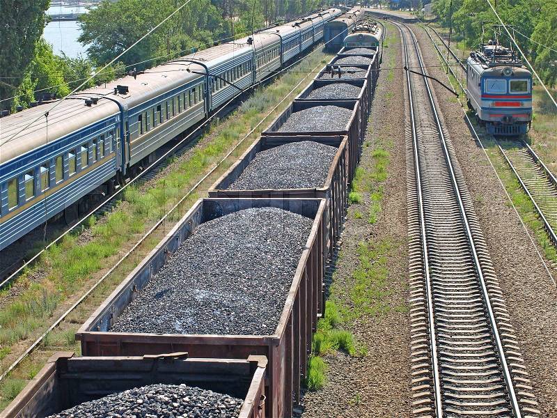 Freight train with coal and passenger train at station on seaside, stock photo