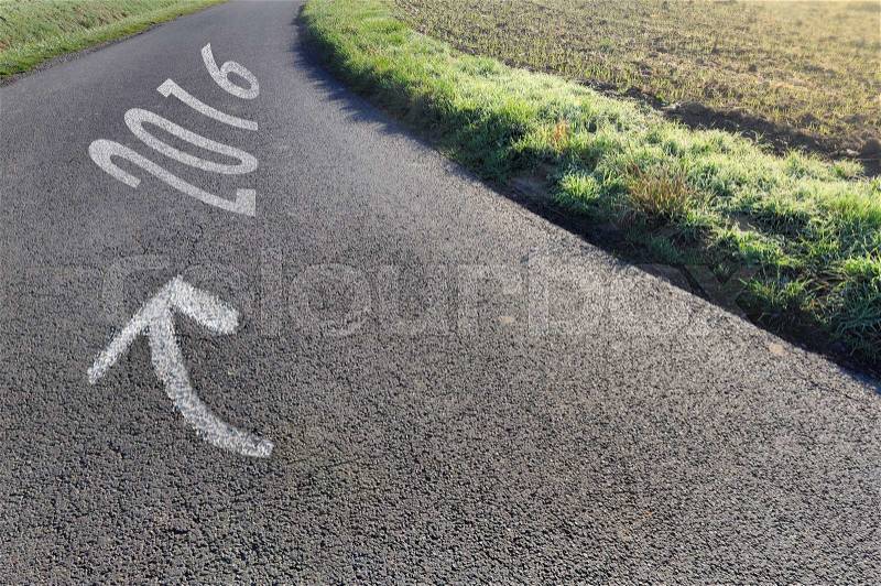 arrow on asphalt country road in a curve pointing 2016 , stock photo
