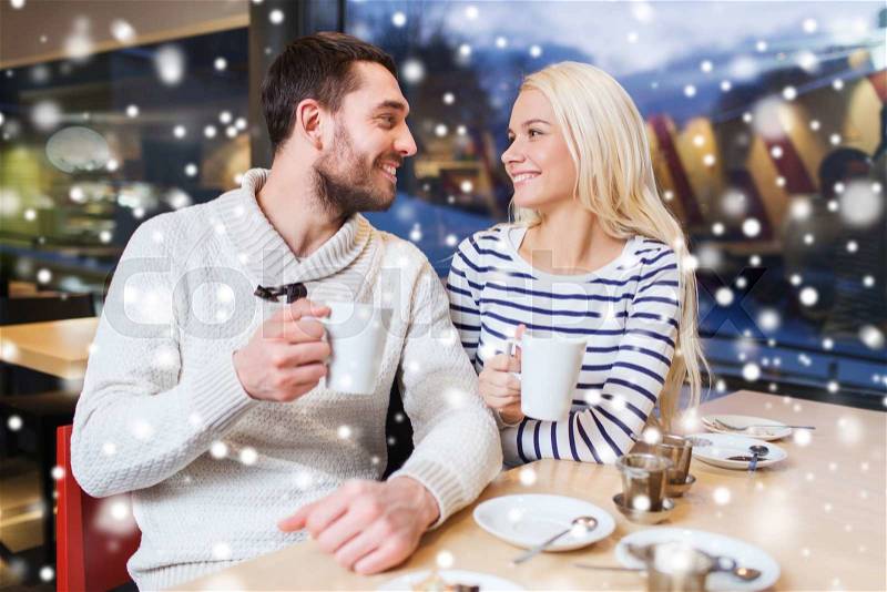 People, leisure, communication and season concept - happy couple meeting and drinking tea or coffee at winter cafe, stock photo