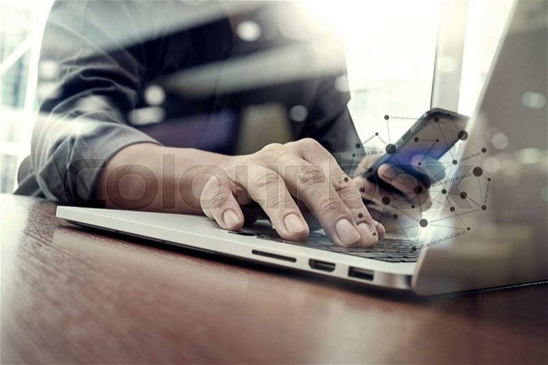 Designer hand working and smart phone and laptop on wooden desk in office with london city background , stock photo