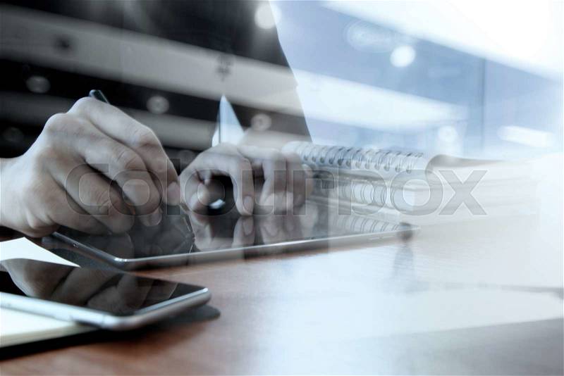 Double exposure of designer hand working with digital tablet and laptop and notebook stack and eye glass on wooden desk in office, stock photo