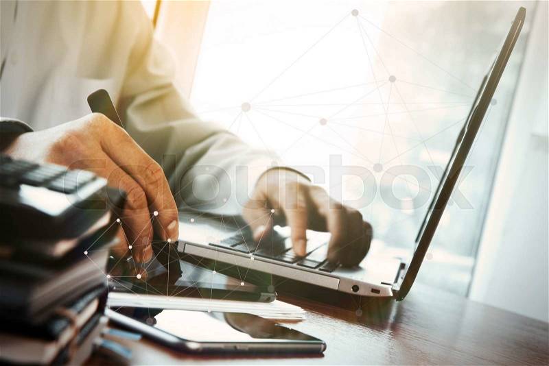 Designer hand working with digital tablet and laptop and notebook stack and eye glass on wooden desk in office with social media diagram, stock photo