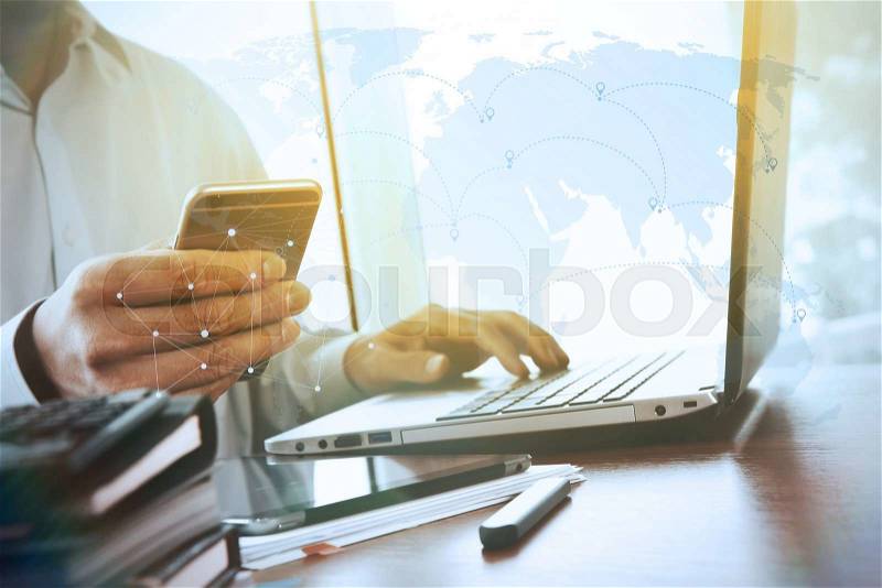 Businessman hand using laptop and mobile phone on wooden desk as concept with social media diagram, stock photo