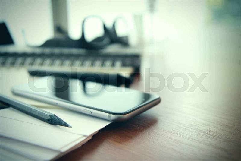 Smartphone close-up, planning book on wooden desk work space concept, stock photo