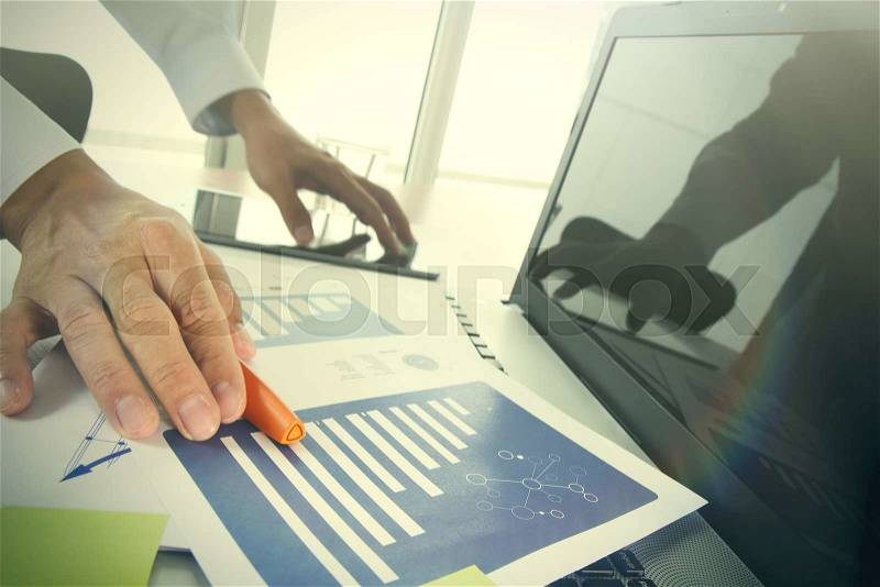 Businessman hand picking up the pen at office and social network media and graph chart diagram as concept, stock photo