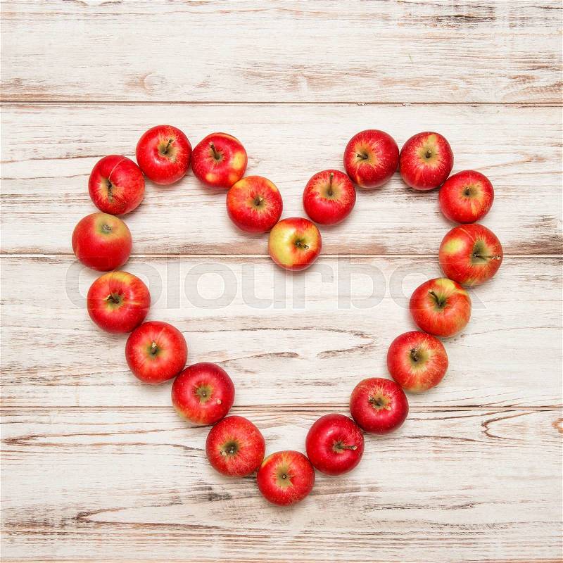 Red apples heart over rustic wooden background. Love concept. Vibrant colors, stock photo