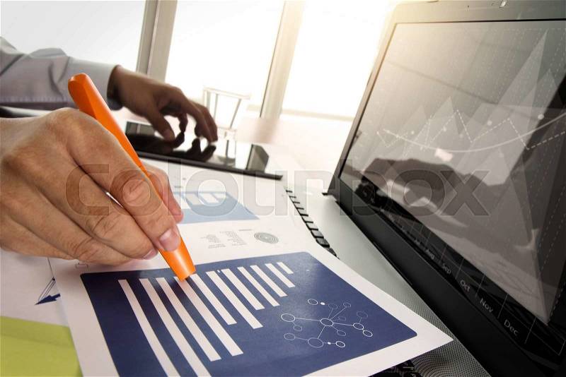 Business documents on office table with smart phone and digital tablet with laptop computer and man working in moment, stock photo