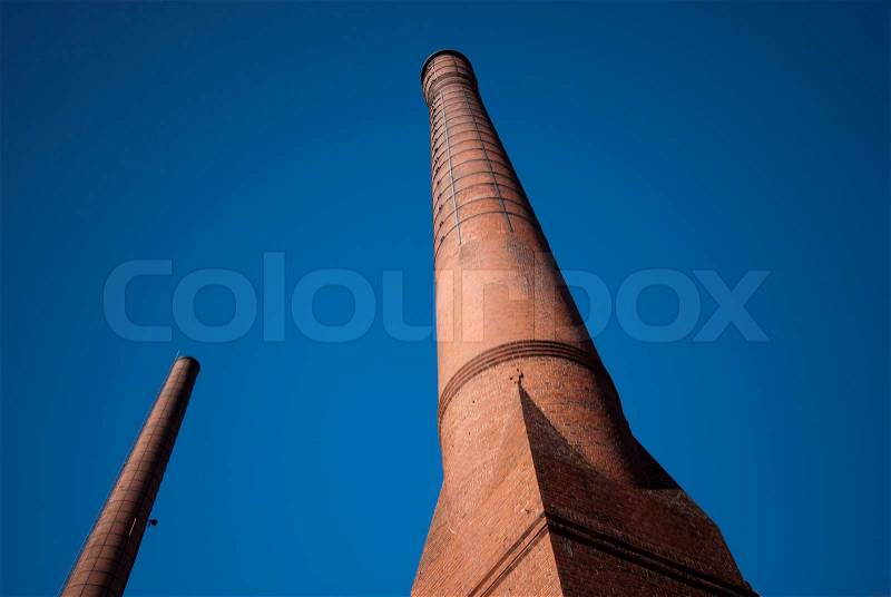 Two brick factory chimneys alone in the blue sky, stock photo