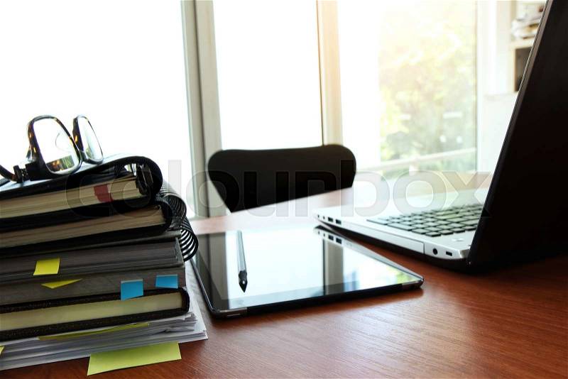 Business documents on office table with smart phone and eye glass and modern pen with laptop computer in workspace concept, stock photo