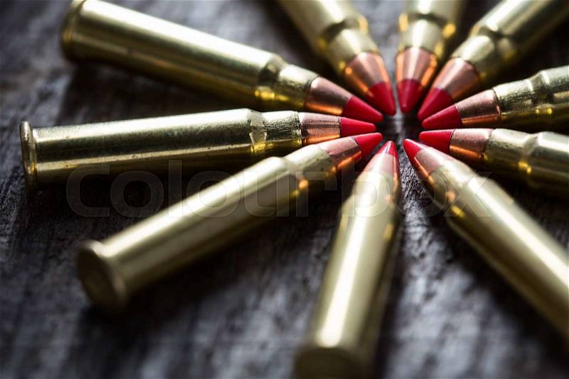 Macro shot of small-caliber tracer rounds with a red tip. Ammunition composition lie in Ida range, on the tops of bullets into the textural wooden background, stock photo