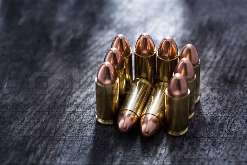 Composition of pistol copper cartridges stacked in a guest chair. Photographed in studio on a wooden textural background, stock photo