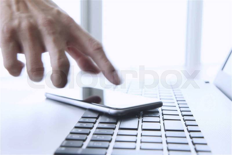 Designer hand working and digital tablet and laptop on wooden desk in office, stock photo