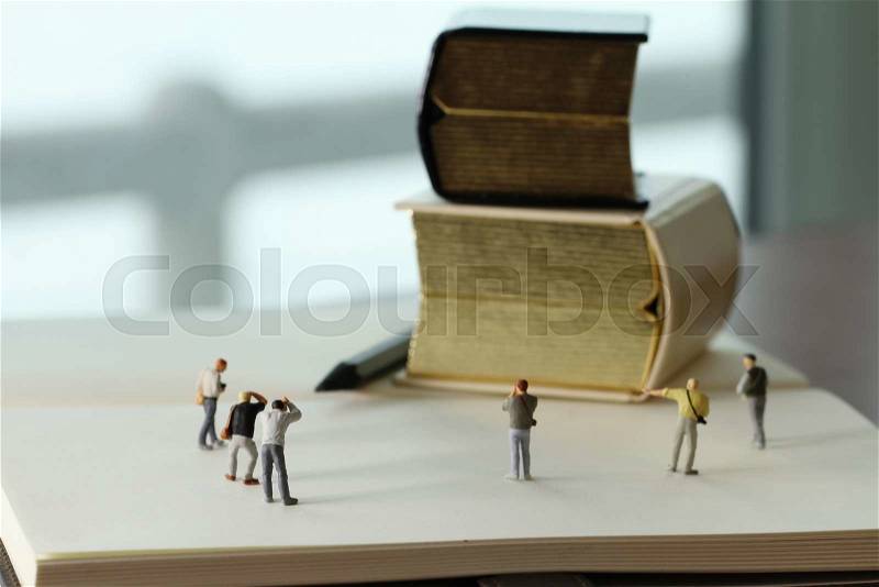 Creative idea concept - miniature photographer with vintage golden book on open paper notebook, stock photo