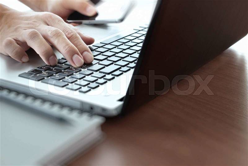 Close up of business man working on laptop computer on wooden desk as concept, stock photo