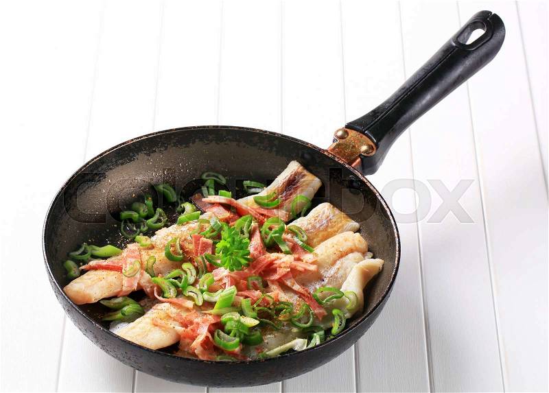 Pan fried fish fillets with bacon and spring onion, stock photo