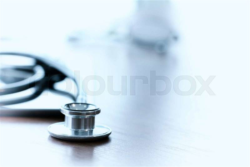 Studio macro of a stethoscope and digital tablet with shallow DOF evenly matched abstract on wood table background copy space, stock photo