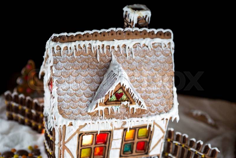 Decorative gingerbread house with lights inside on black background. Rural Christmas night scene, stock photo
