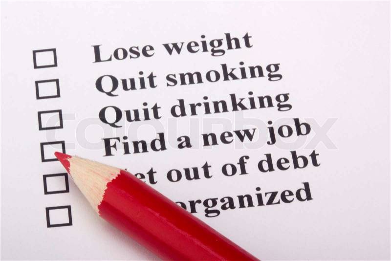 A red pencil laying on a paper with a list of goals, stock photo