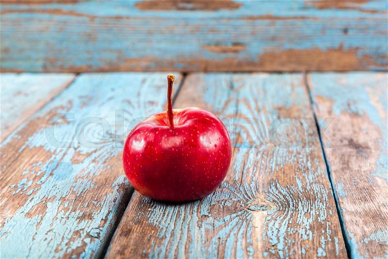 Fresh apple on painted blue wooden boards, stock photo