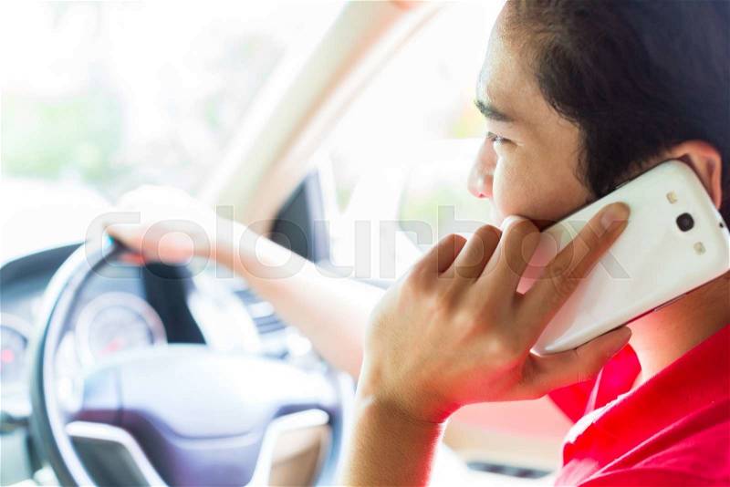 Asian young man telephoning with mobile phone or smartphone while driving car , stock photo