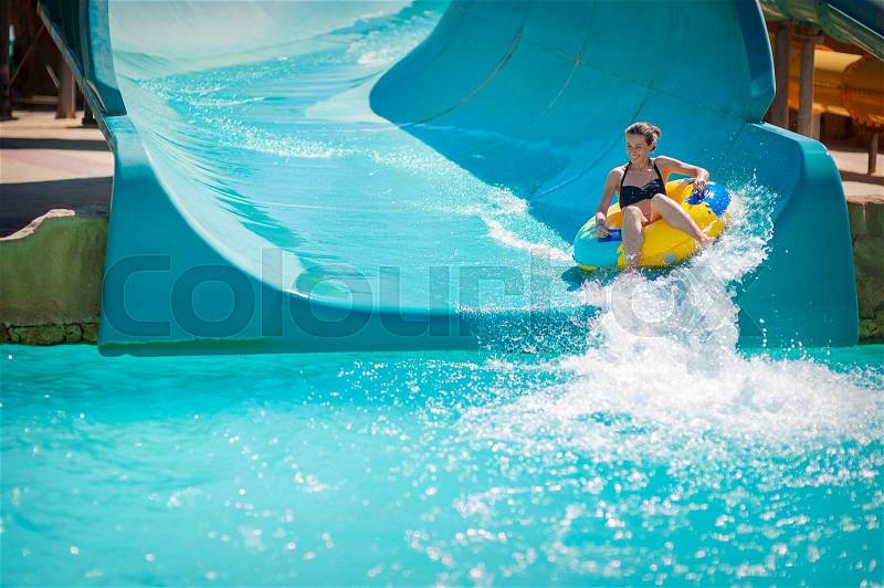 Beautiful girl pulls off the slides at the water park, stock photo