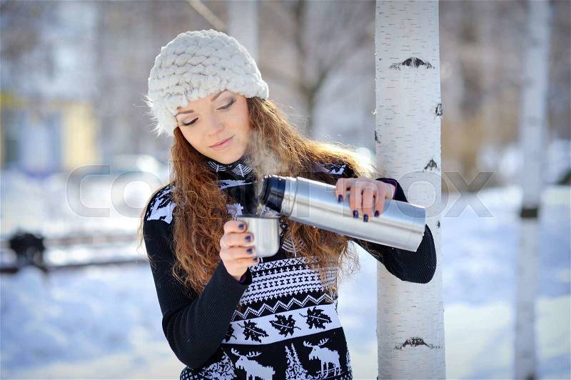 Beautiful girl with thermos and cup hot tea in frosty winter day , stock photo
