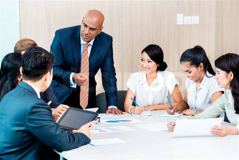 Diversity team in business development meeting with charts, Indian CEO and Caucasian executive crunching numbers, charts and figures on the desk, stock photo