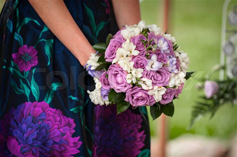 Beautiful bouquet of purple roses in their hands, stock photo