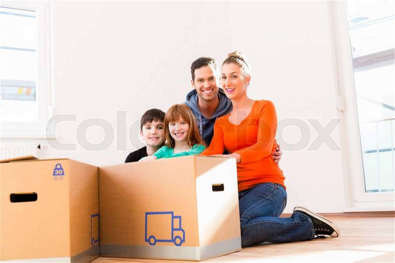 Family unpacking moving boxes in new home, stock photo