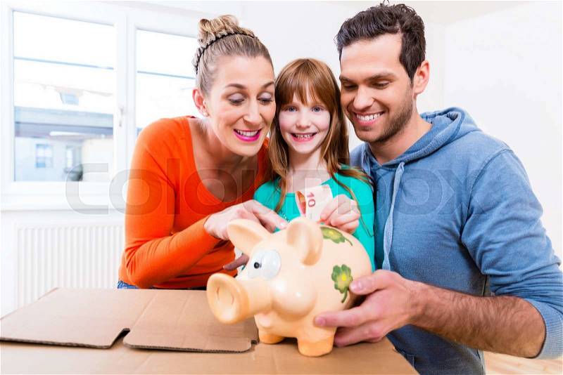 Family saving money by moving house putting bank note in piggybank, stock photo