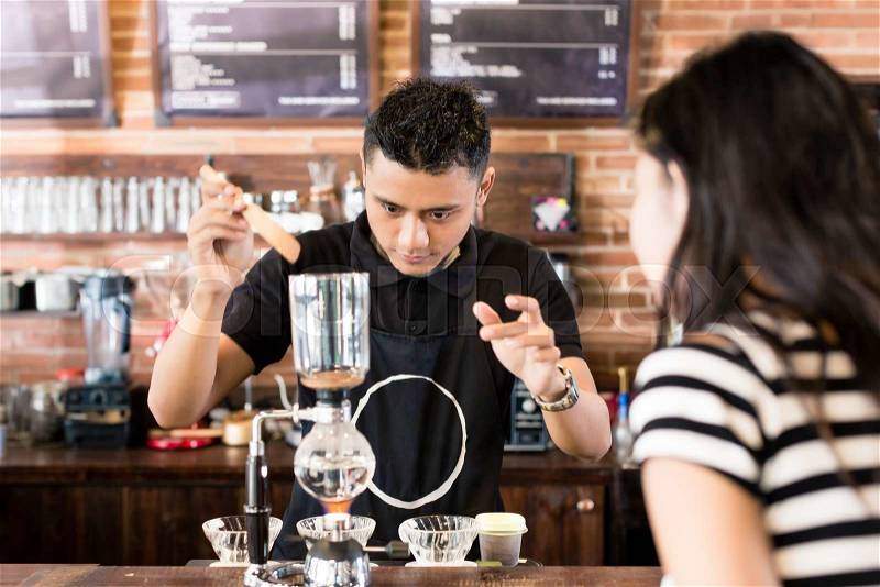 Woman watching barista preparing drip coffee in cafe, stock photo